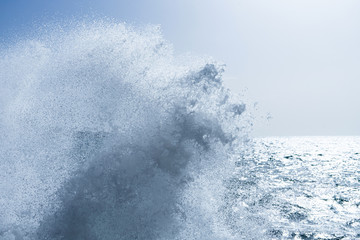 Water splashing. Crystal clear sea water beating against the rocks and cliffs. Sea waves break on the shore after a storm. Blue sky, sunny summer day, refreshing mediterranean sea water