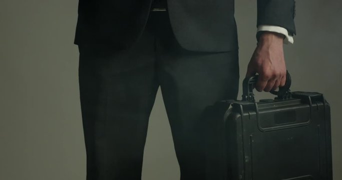 Man in business suit has briefcase full of secret documents handcuffed to wrist - close up