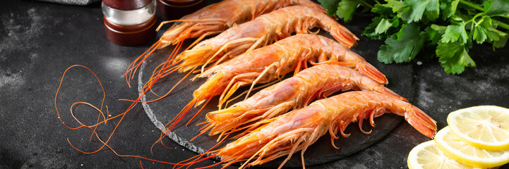 Large langoustines on a black plate on the black kitchen table. Seafood for a healthy diet. Banner