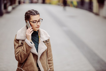 Fototapeta premium Attractive brunette having phone conversation on the street. She is worry.