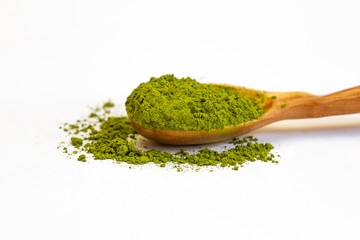 Green tea matcha in a wooden spoon on a white background close-up. Dry green tea. Macro of a matcha. Side view.