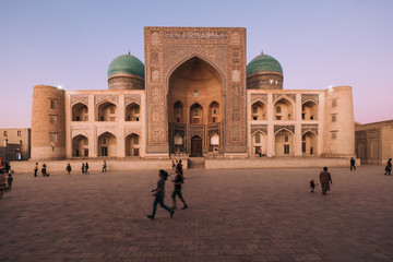 Middle Asia. Uzbekistan Bukhara. Summer. Eastern mosque. Poi Kalyan complex. The main building. Against the background of children running