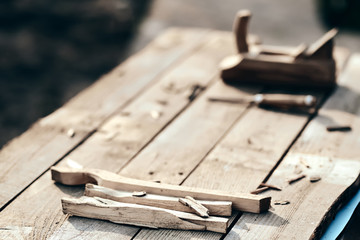 wooden background. On the village table lie dotches, sawdust, and on the background of the bit and jointer plane. Wood thread tool. solar lighting