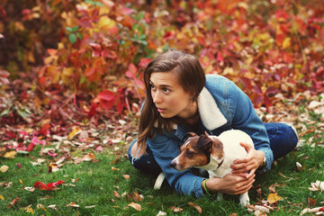 Fototapeta premium Dog and owner walk autumn park. Purebred Jack Russel Terrier dog outdoors in nature on grass on autumn day. Playful mood. Funny expressive leisure time. Breeder and his pet at training. Pets friends.