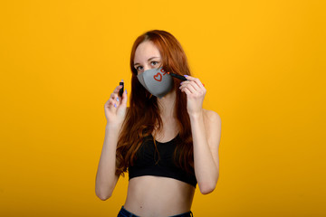 Obraz premium Portrait of a girl in a mask, which puts on a rubber glove. Yellow background.