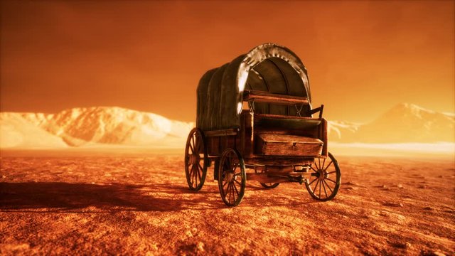 canvas covered retro wagon in desert at sunset