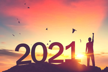 Man raise hand up on sunset sky with birds flying at top of mountain and number like 2021 abstract background. Happy new year and holiday concept.
