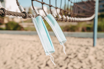 COVID-19 Surgical mask hanging on the net of an empty beach volley field