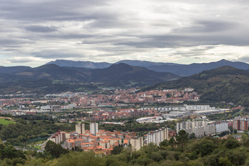 Fototapeta na wymiar The largest city of the Basque Country. Top view on Bilbao. Panorama of the big city. Red tiles of a European resort town. Roofs of houses. City at the foot of the mountains.