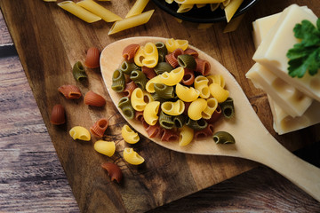 Different raw uncooked Italian pasta and cheese on wooden table. Diet and food concept.