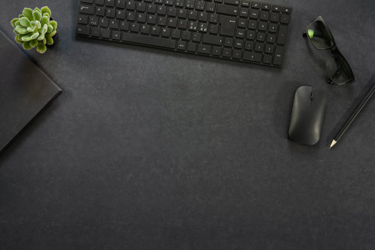 Top view of black concrete office desk with computer and supplies