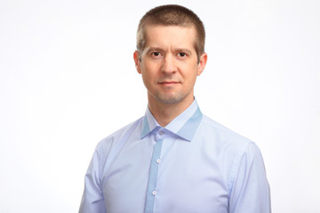 A serious man in a light shirt looks into the camera. Isolated