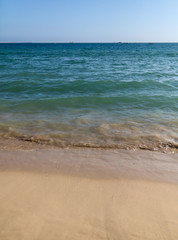 Fototapeta na wymiar The blue sea separates the sky and the sandy shore.