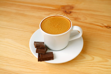 Closeup a Cup of Espresso Coffee with Dark Chocolate Cubes Isolated on Wooden Table
