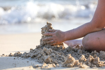A boy plays in the sand on the beach near the sea.