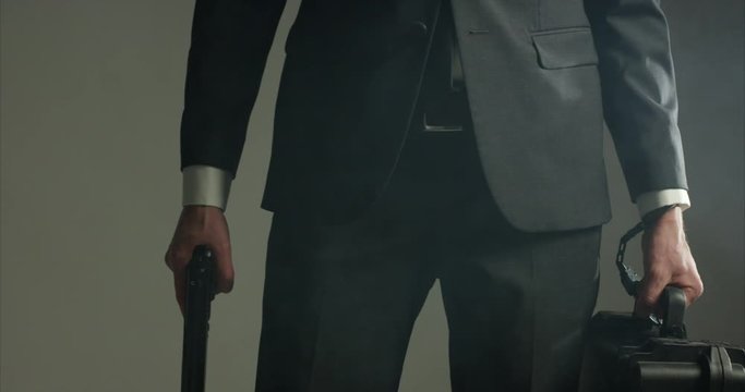 Secret service man cuffed to military briefcase with gun in other hand - close up