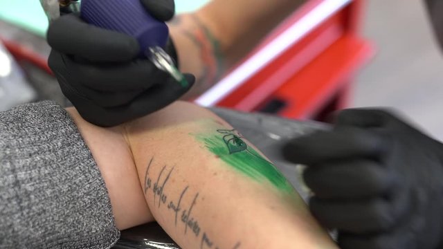 Female tattooist tattooing a peach on a woman's arm.