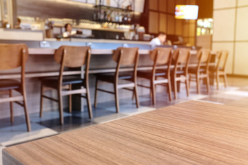 Wooden board empty table top in front of blurred cafe or restaurant background, for display and mockup or montage products