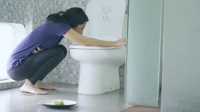 Asian woman vomiting after eating in bathroom