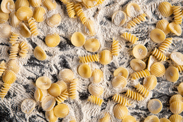 Pasta in flour on a black background. Top view.