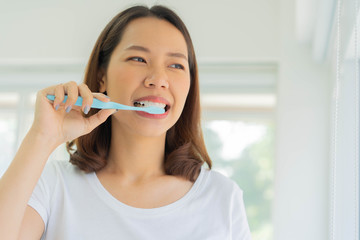 close up young asian woman using toothbrush to brushing teeth at bathroom in the morning fro healthy and routine life concept