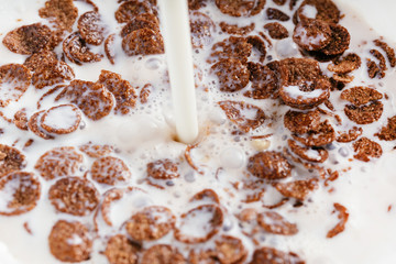 Bowl of chocolate flakes with milk splash. Top view.