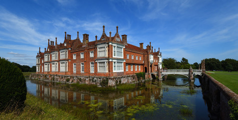 Fototapeta na wymiar Helminngham Hall with moat bridge and reflections.