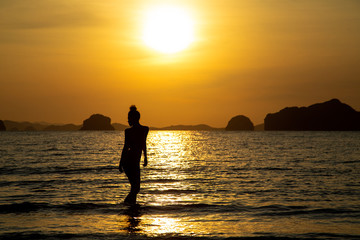Fototapeta premium Silhouette of a girl on the beach, against the backdrop of the sea and sunset