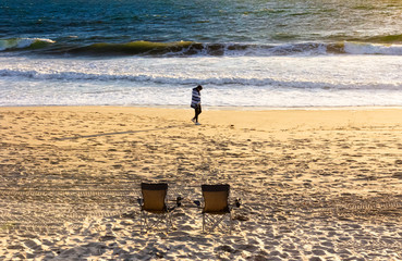 Man wrapped in blanket walking across ocean coast