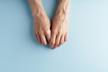 Hard-working hands with protruding veins on blue background.