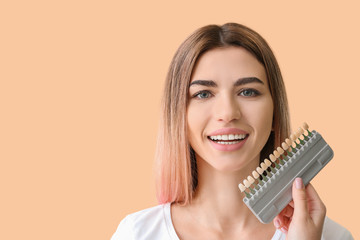 Beautiful young woman with teeth samples on color background