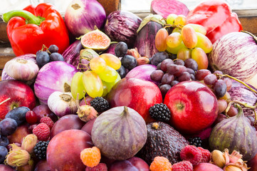 Background of fresh vegetables and fruits. Purple eggplant, plums, figs, apples, raspberries, avocado, grape, hazelnut, sweet pepper, tomato and garlic.Immunity system improvement. Antiviral treatment