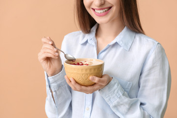 Young woman with tasty yogurt on color background