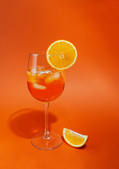 Cocktail aperol spritz with ice. In a glass goblet. On a glass of orange slice. Next to the glass is a slice of orange. 