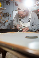 Male carpenter working on old wood in a retro vintage workshop.
