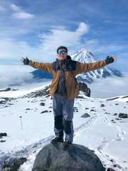Happy russian man in polarized glasses with backpack stands on the rock with open arms near the...