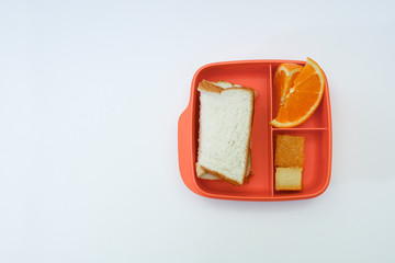 Sandwich, cake, and orange slices in a food container on white background 