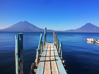 Embarcadero en Panajachel sobre el agua del Lago Atitlán, al fondo los volcanes San Pedro, Atitlán y Tolimán a primera hora de la mañana