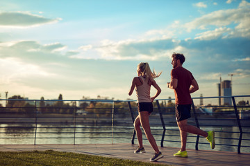 Modern woman and man jogging / exercising in urban surroundings near the river.