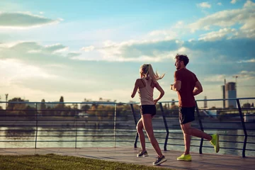 Fotobehang Modern woman and man jogging / exercising in urban surroundings near the river. © astrosystem