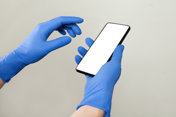 Doctor hands in medical gloves using smartphone on white background