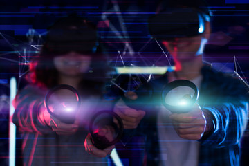 Closeup hands are holding wireless controllers. Boy and girl are playing in virtual reality game club. Young friends in VR glasses are gaming. Entertainment and leisure concept. Modern technologies.