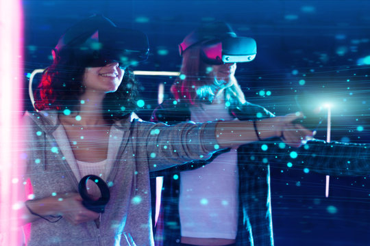 Boy and girl are playing in virtual reality game club. Young woman and man in VR glasses are gaming with holograms using wireless controllers. Entertainment and leisure concept. Modern technologies.