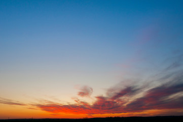 Panorama of dawn fire in the sky above the natural pasture. Golden red clouds just before sunrise. Picturesque landscape at sunrise. Beauty in nature