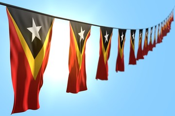 beautiful memorial day flag 3d illustration. - many Timor-Leste flags or banners hangs diagonal on string on blue sky background with selective focus