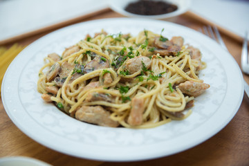Mushrooms over spaghetti . Raw spaghetti pasta inside a bowl . Black pepper, Mayonnaise inside a bowl. Forks . Uncooked spaghetti . Delicious spaghetti wooden tray .