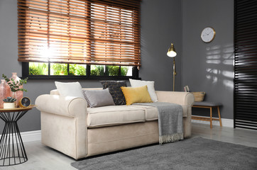 Stylish living room interior with comfortable sofa near window