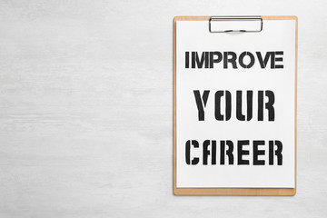 Clipboard with words IMPROVE YOUR CAREER on white wooden background, top view. Space for text