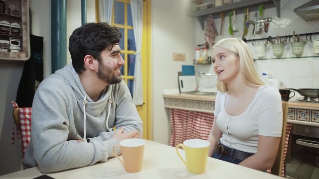 Young couple talking and drinking tea together on a kitchen