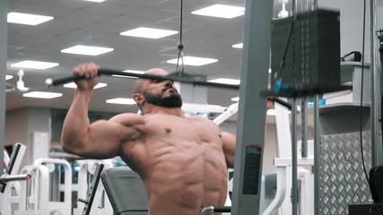 Medium shot strong athletic men doing front pull-downs on machine in gym. Sports healthy lifestyle strength and beauty. fitness bodybuilder with the naked torso training sports hall.